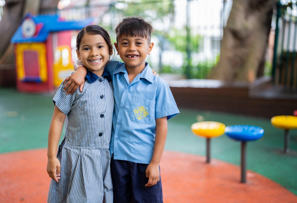 Two primary school friends in a school playground. Friendships and a growth mindset help to grow students' resilience.